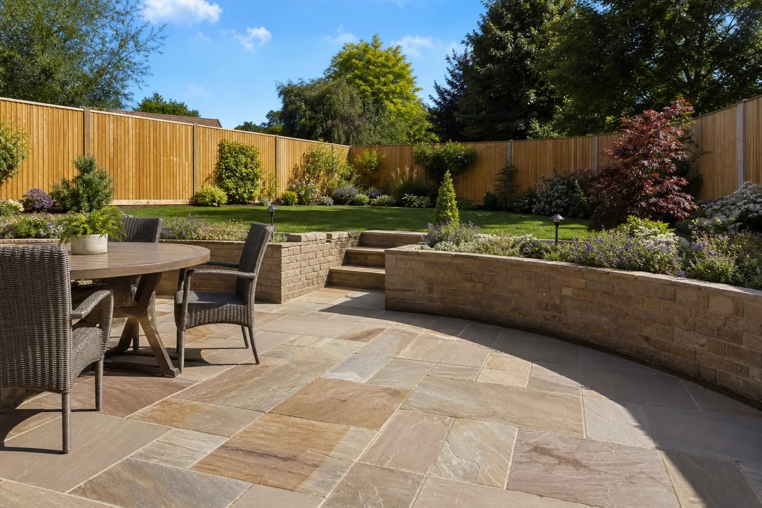 Landscaped garden with a paved patio, retaining wall and neat planted borders